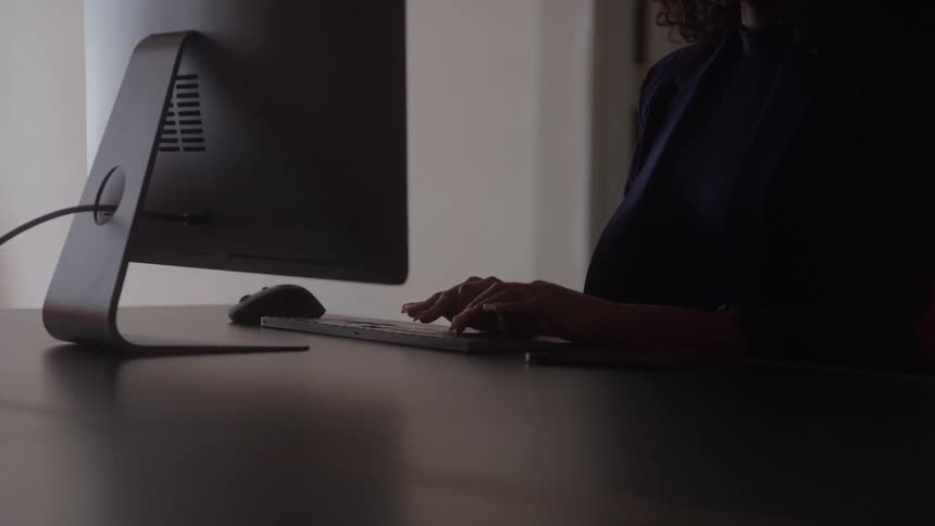 A woman sitting and working in an office typing on a computer keyboard