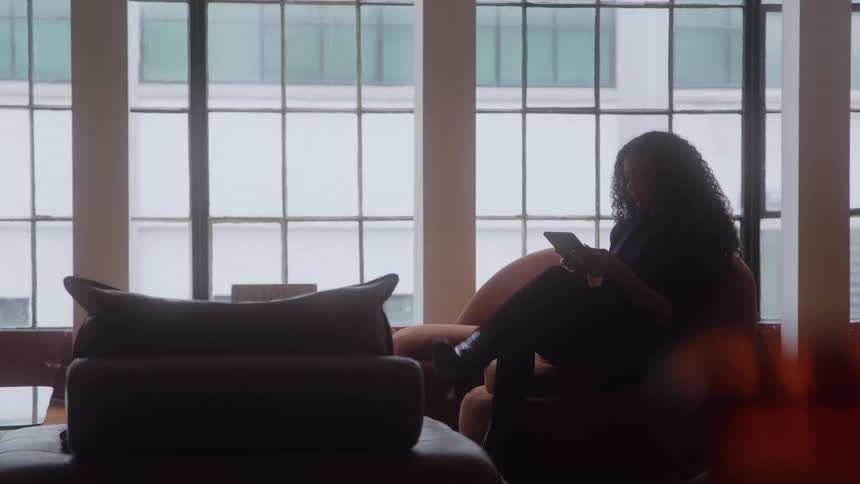 Woman sits by the window reading in a room lit by natural light