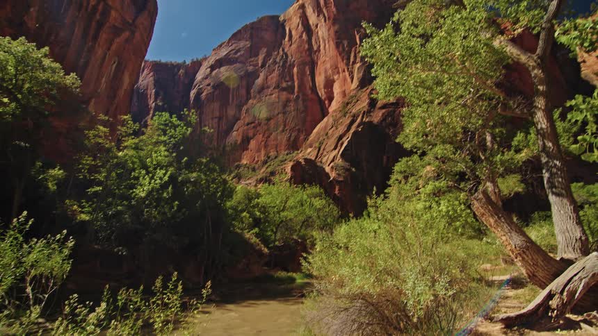 Group of people in sportswear walk along a trail near a river in a canyon