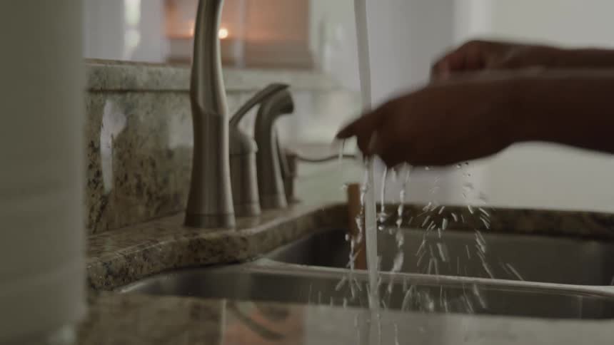 The woman is cleaning her hands in the kitchen sink