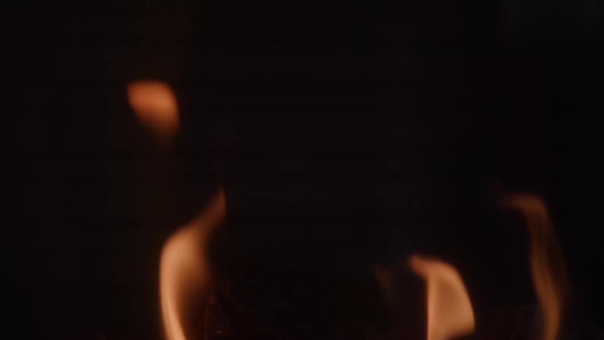 Yellow flames spring up and burn out into the night casting flickering light against the darkness