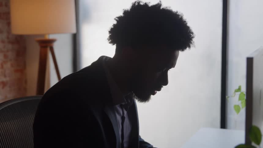The man leans forward in front of his computer in the office