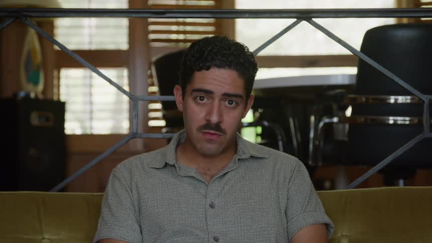 Man sitting on the couch looks down in a moment of reflection