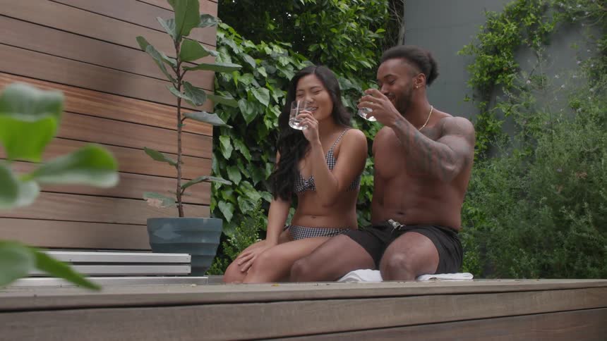 A young couple drinking cups of water while sitting together outdoors during daytime