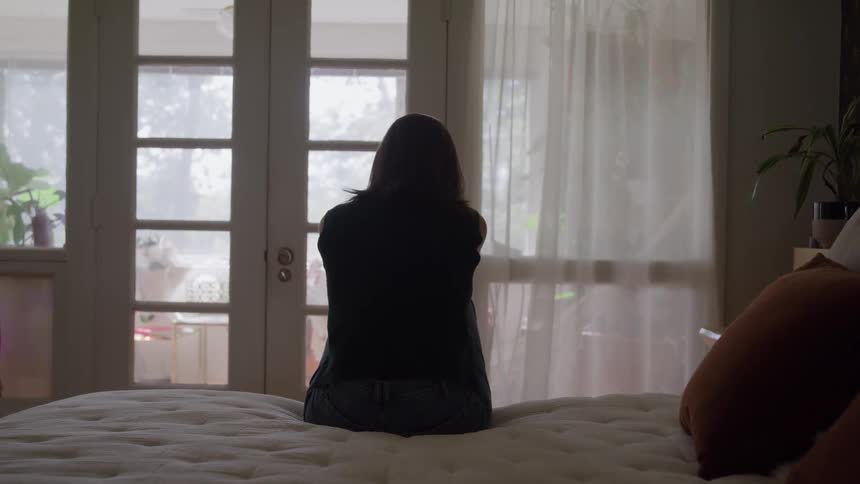 The woman is sitting on the bed