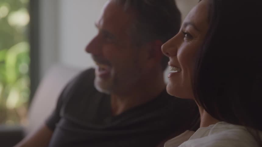 Couple smiling while sharing a relaxed moment on the couch