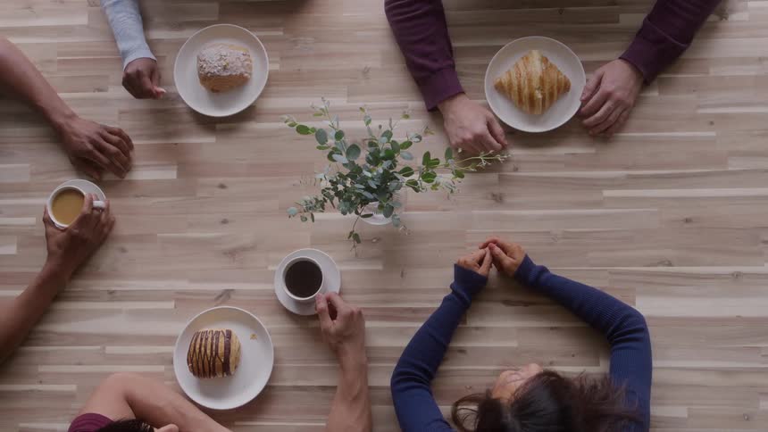 A group of friends conversing while eating at a table in a cafeteria during daytime