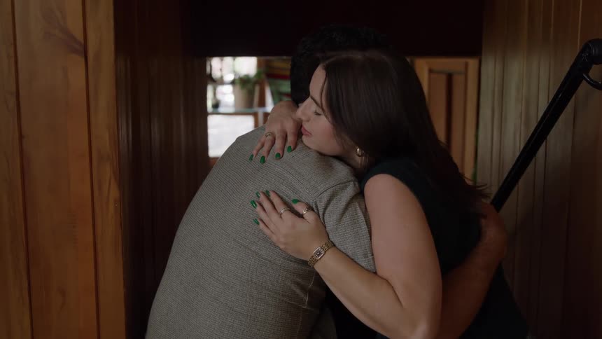 Two people hug in a wooden setting with soft lighting