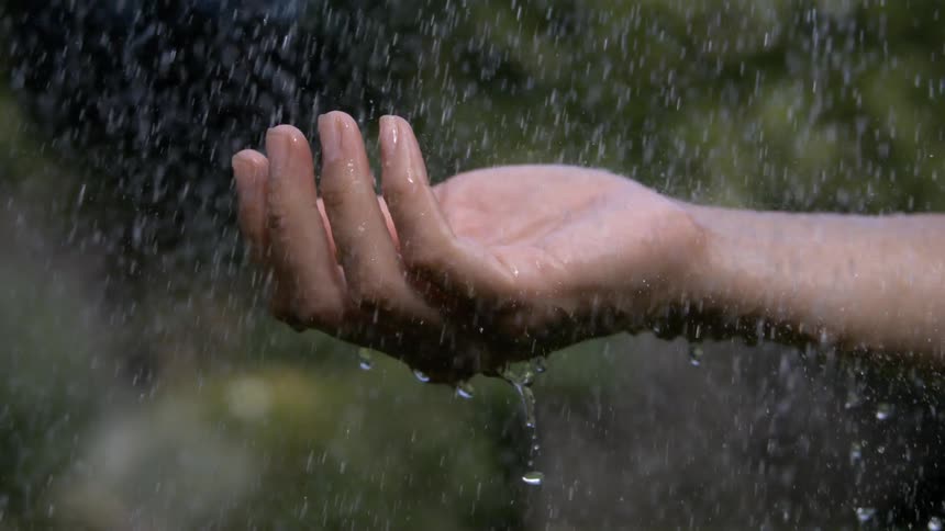 Outstretched hand feels the raindrops falling slowly