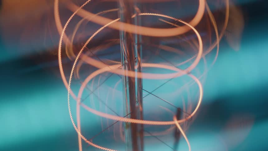 Spiral incandescent filament emitting orange light against blue background