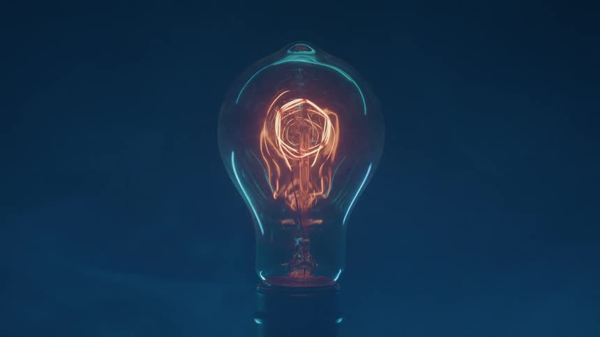 The video shows an antiquestyle incandescent light bulb against a dark blue backgroundthe bulb is initially lit with its glowing filament emitting a warm orangeyellow light over the course of the video the light dims and the filament cools down