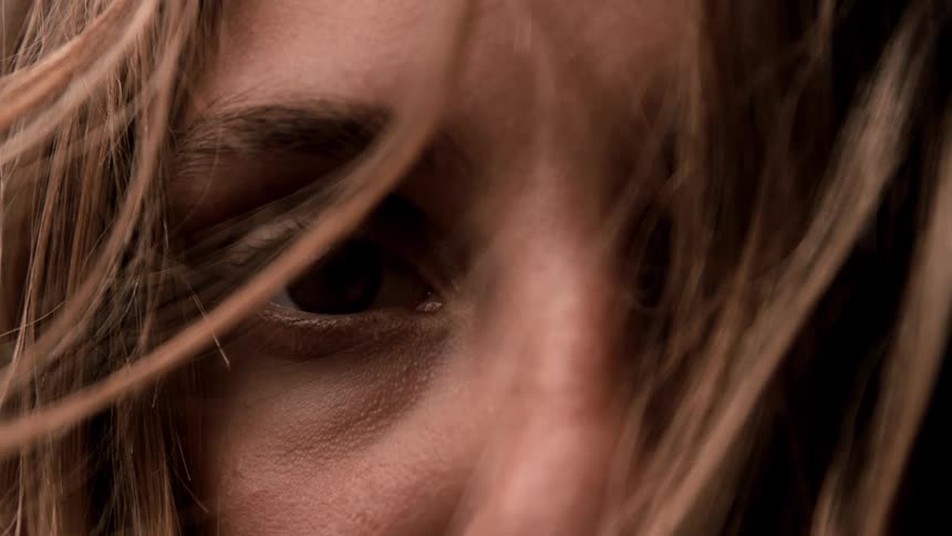 Long brown hair moves in the breeze across a womans face