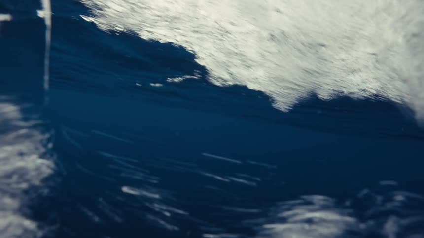 Closeup of turbulent white water swirling over a dark blue background