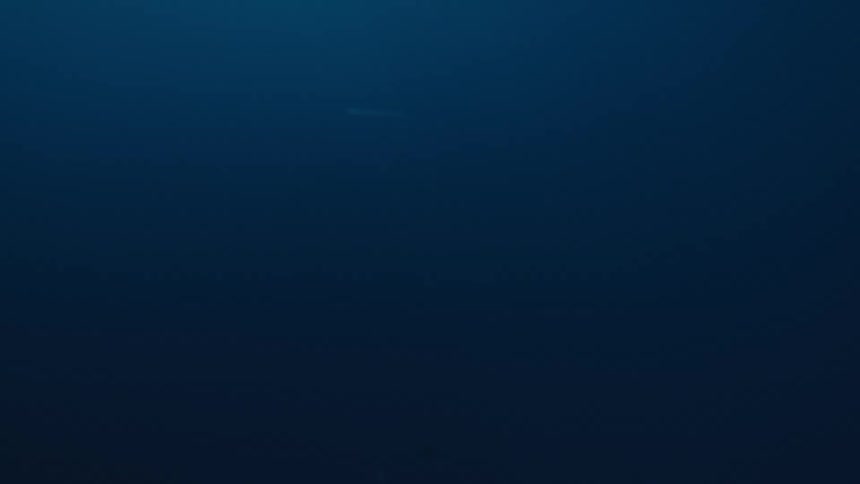 This footage initially features a dark blue calm underwater environment with a faint stream of bubbles descending from the surfacemidway through the camera quickly breaks the surface and shows a lowangle fastmotion view of turbulent whitecapped