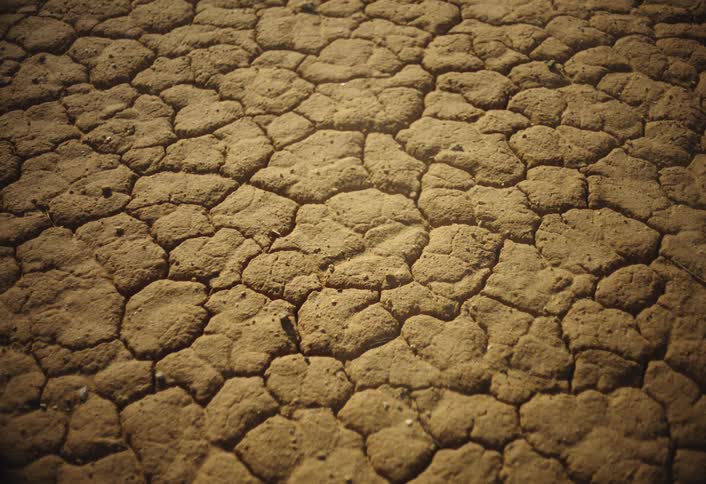 A desert landscape with dry cracked soil under the blazing midday sun