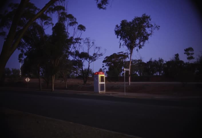 Pickup truck drives past a phone booth at night
