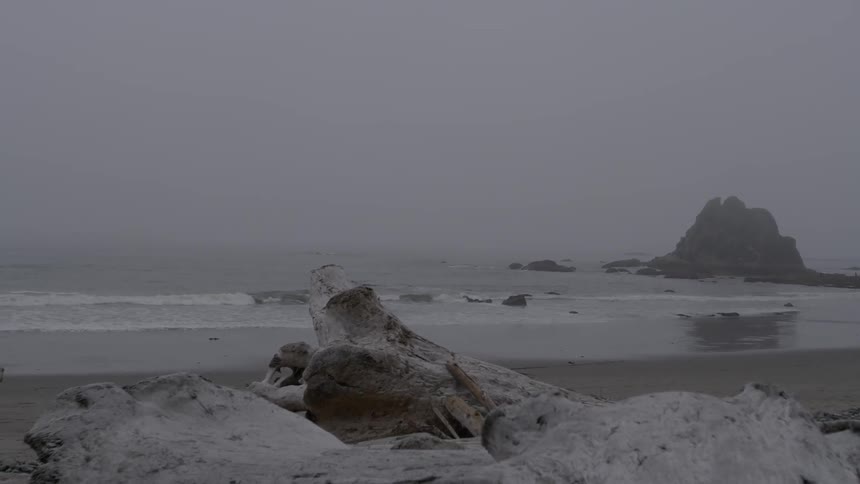 Ocean water flowing onto beach on foggy day