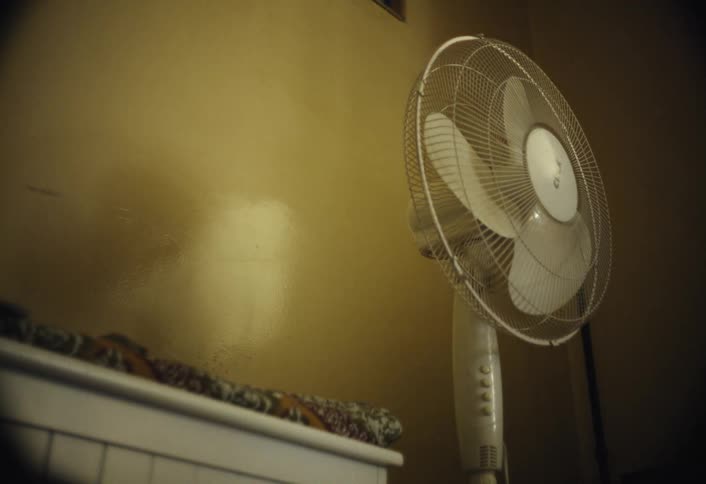 The white fan is up against the wall