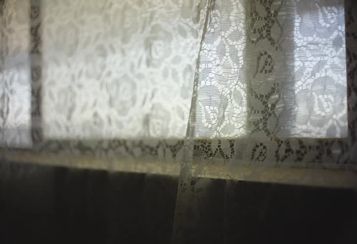 Curtain over a window moves in the breeze
