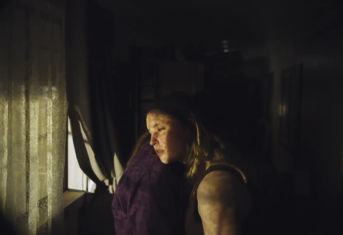 Woman looks out the window while lying her head on the shoulder of the person hugging her