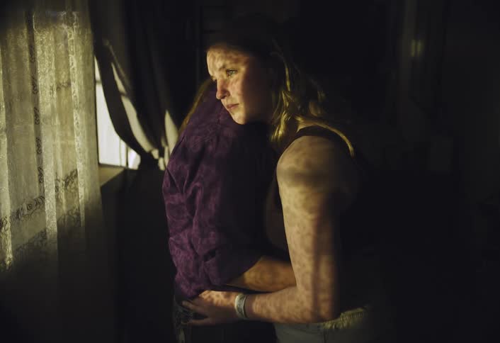 Daughter stares out the window while she and her mother hug