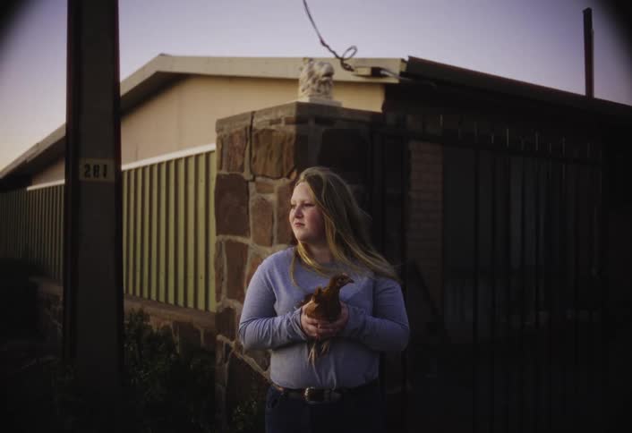 The girl is holding a chicken on the farm