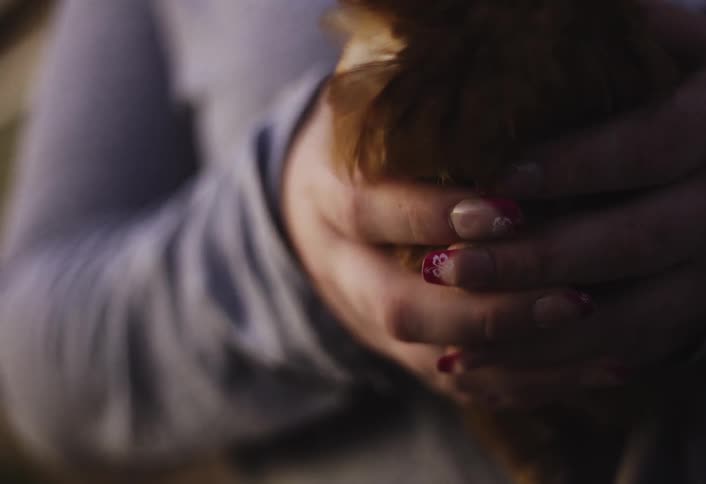 The girl holds a chicken in her two hands