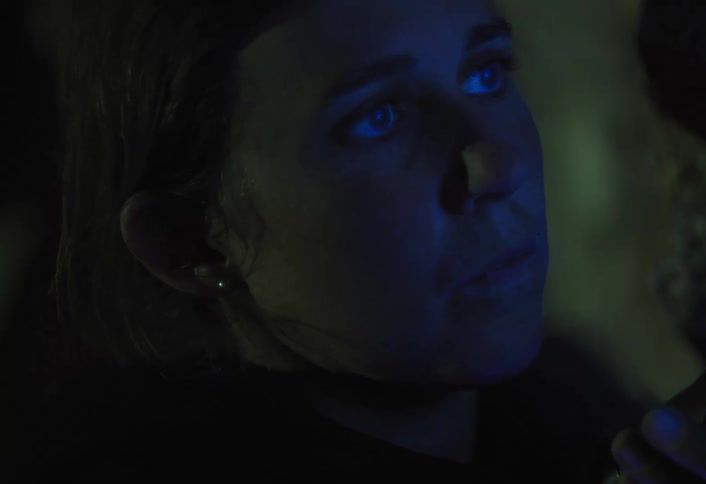 Woman uses a flashlight to explore an earthen wall in the dark