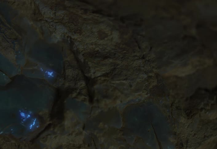 A macro shot reveals a rough earthy rock face with deep crevices highlighting scattered crystallinelike mineral deposits that emit a bright internal blue glow