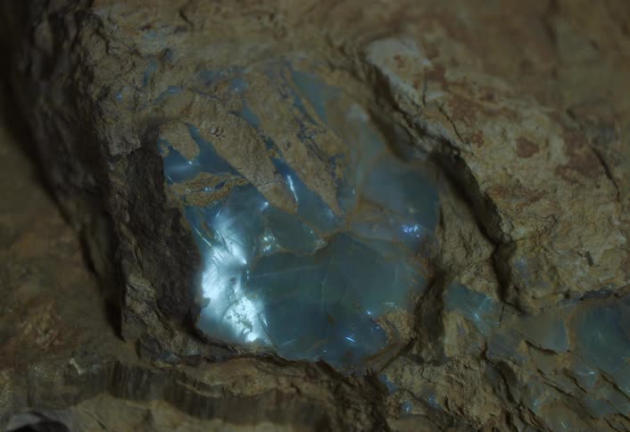 Bluish crystals shimmering inside a dark rock
