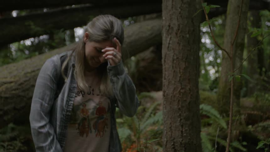 A woman smiles while walking in the woods