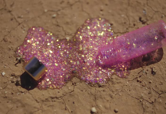 Fingernail polish spilled on the ground contains glitter that sparkles in the sunlight