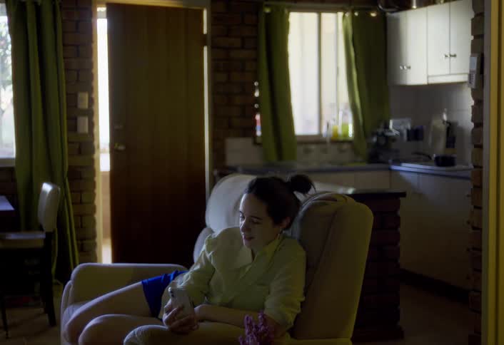 The woman is talking with someone on her cell phone while sitting on the couch