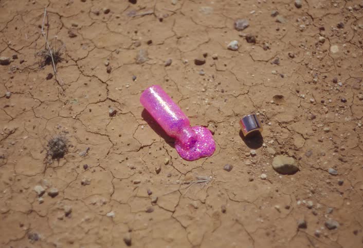 Spilled pink nail polish on dry cracked ground