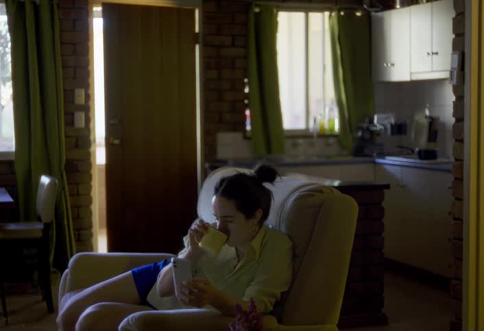 The woman drinks coffee while using her phone