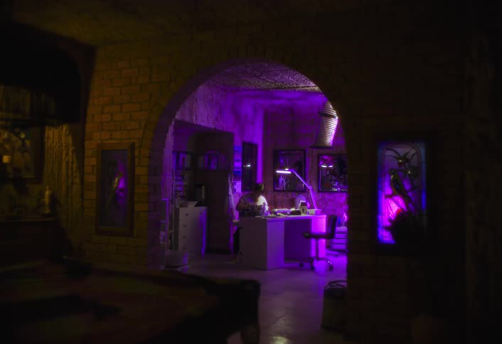 The purple light shines on the man sitting at a desk