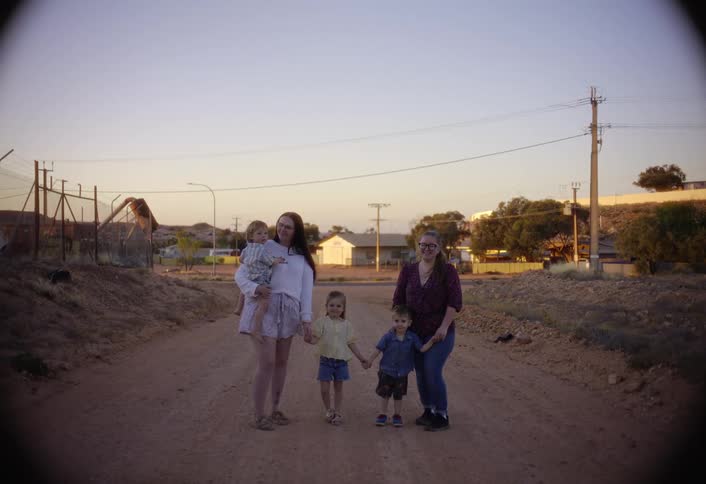 The family stand together smiling on the dirt road