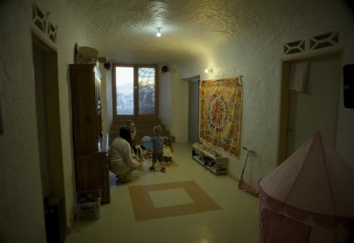 A small boy plays with a balloon in a hallway with others