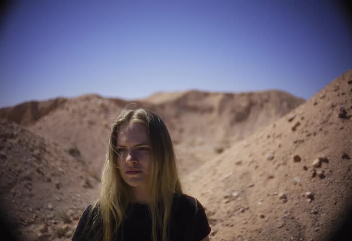 A woman is standing near tall sand dunes