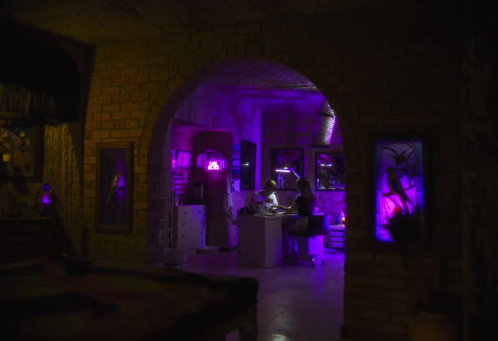 The woman is getting a manicure in the room with purple lighting