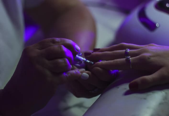 The man paints the womans nails