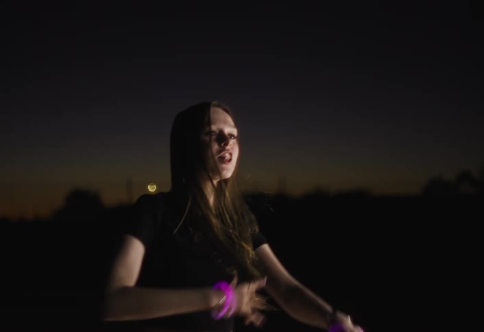 Woman gestures and sings while outdoors at night