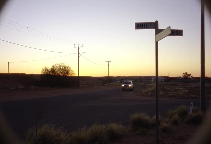 Vehicles pass each other near a rural intersection in the evening