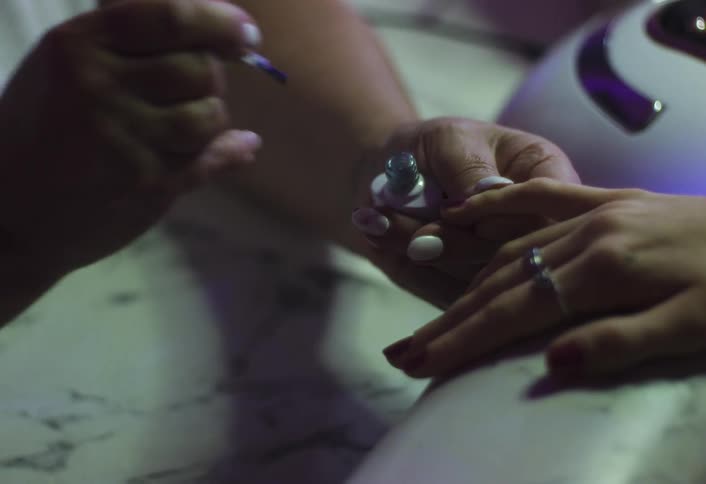 Manicurist paints the fingernails of her female client