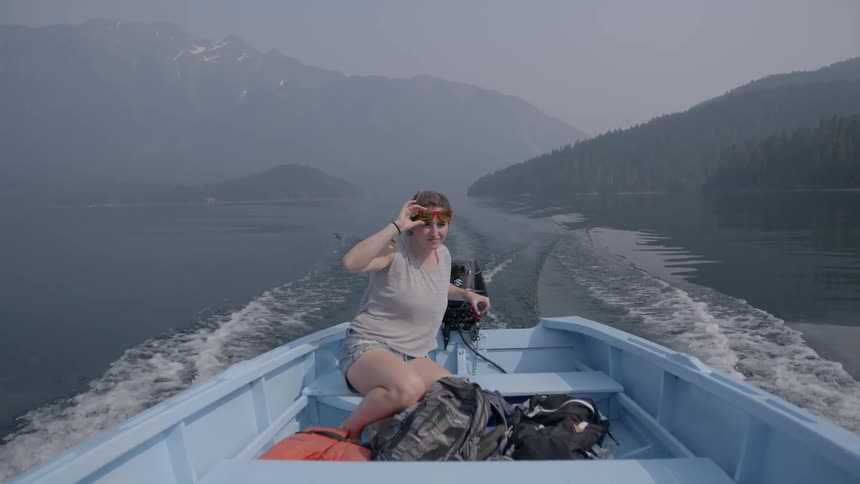 A woman is steering a boat by the motor and moving fast over the water