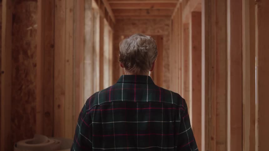 The man walks down the hall of the home under construction
