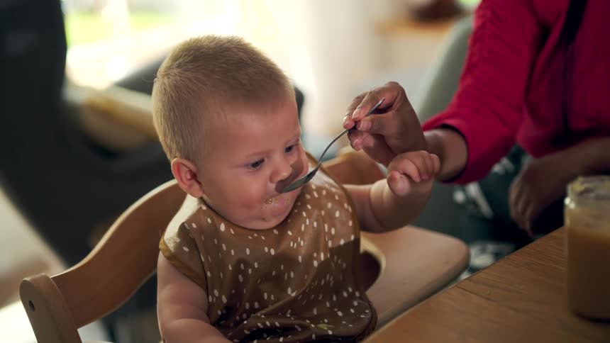 The baby is being fed at the table