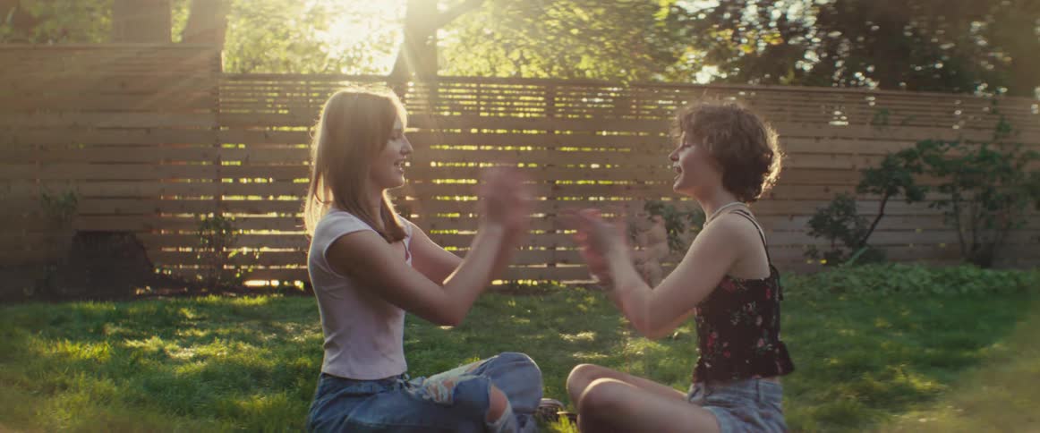 Two teenage girls are sitting in a backyard while playing miss mary mack
