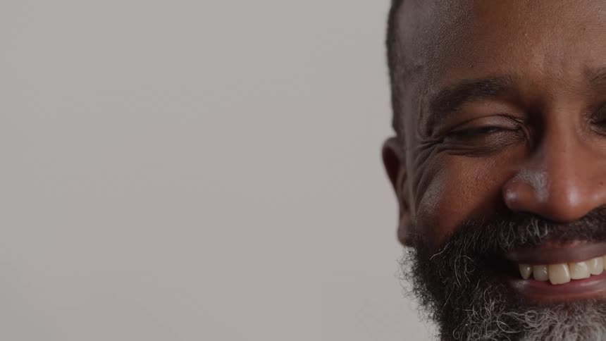 A middleaged man with a bearded face and grayandwhite beard smiling showing his teeth