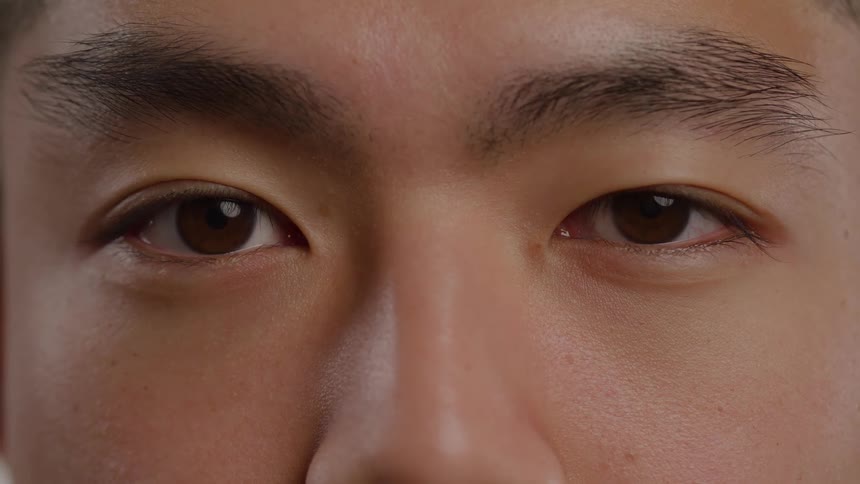 Asian man with his eyes closed then opening them indoors